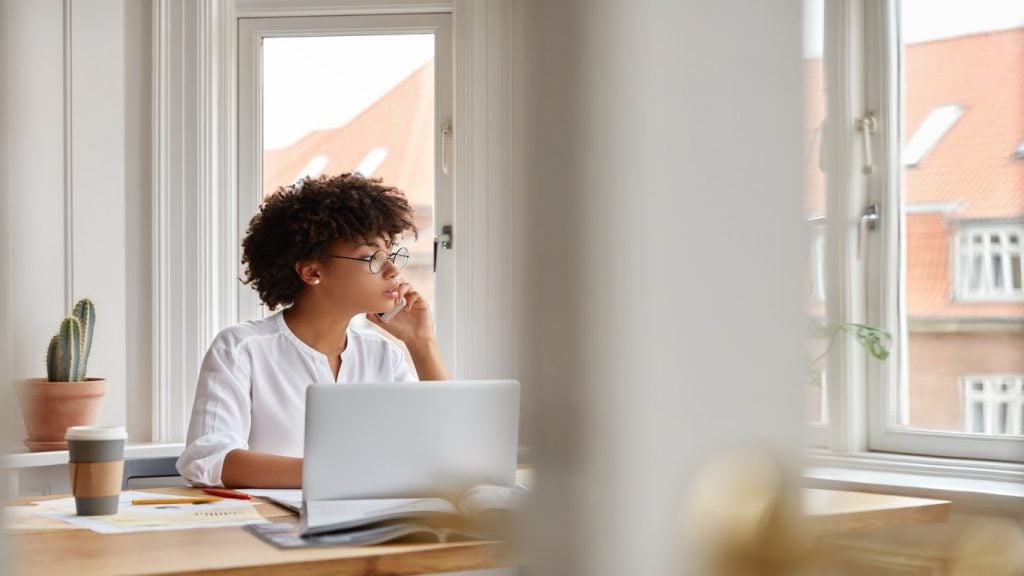 photo female entrepreneur speaks via cell phone looks thoughtfully into window analyzes paperwork from accounting department